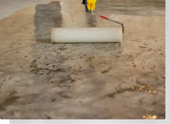 Applying concrete coating primer with roller on bare floor surface