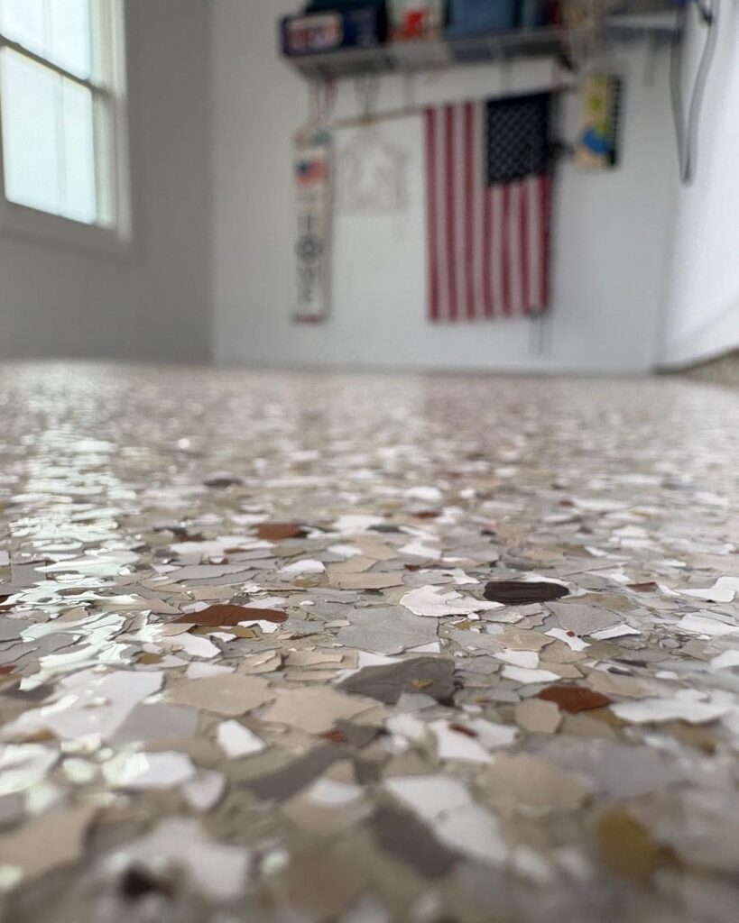 A close-up of a speckled floor in a room with an American flag on the wall and various items on a shelf.