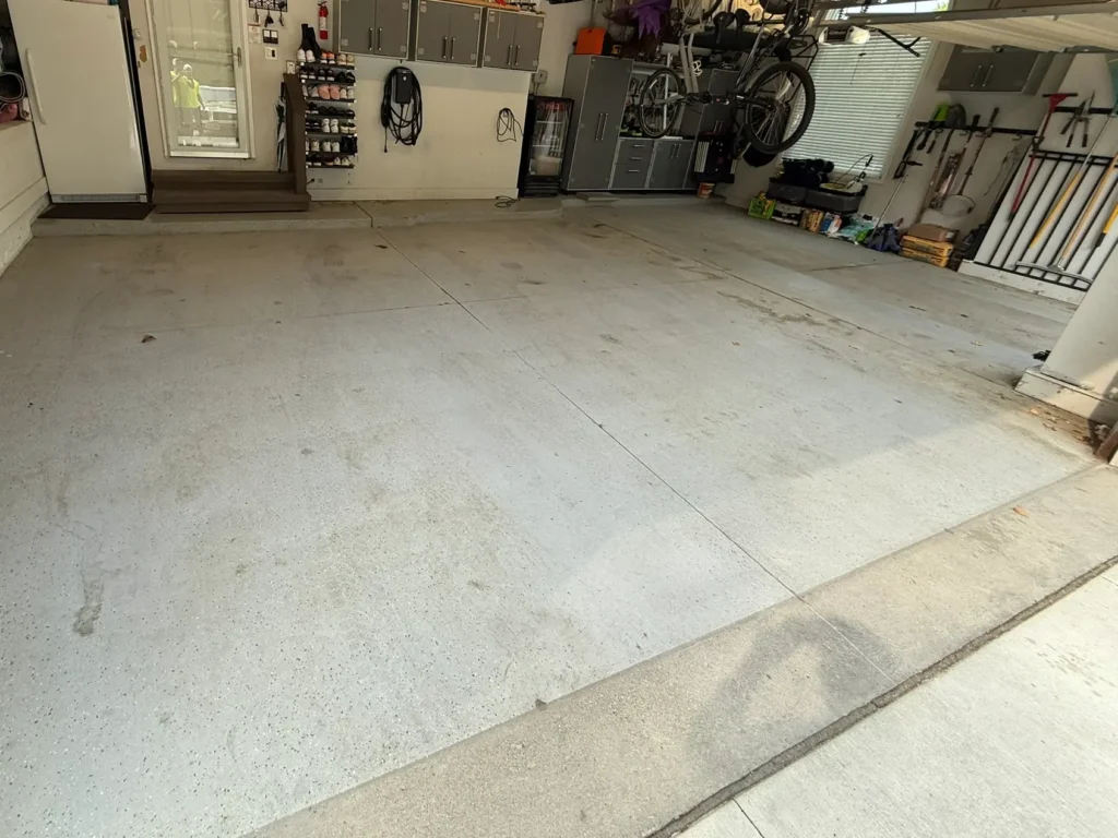 A clean garage with organized shelves, tools, and bicycles. A person is visible through a glass door, standing outside on a small porch.