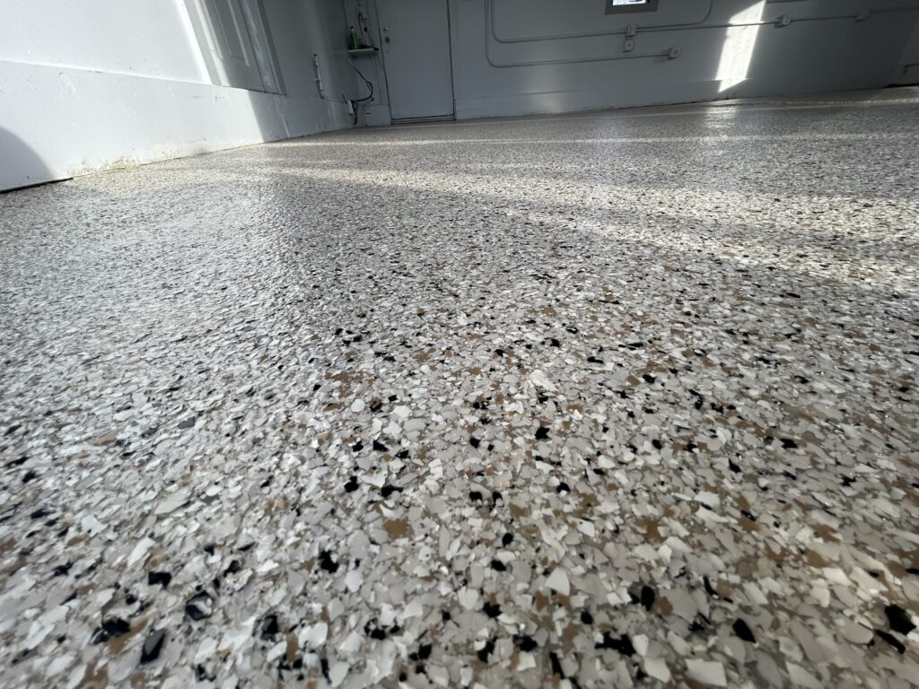 Full broadcast decorative flake epoxy flooring in black, white, and tan blend